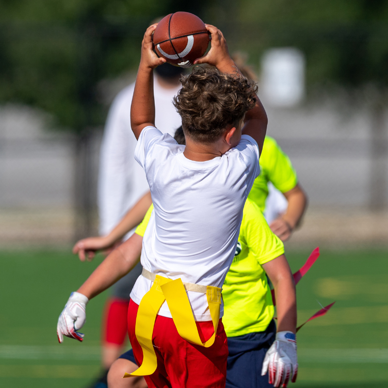 Boy catching a football during a flag football game