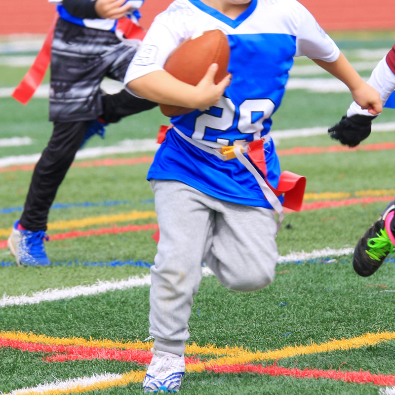 Boy running with a football during sports camp