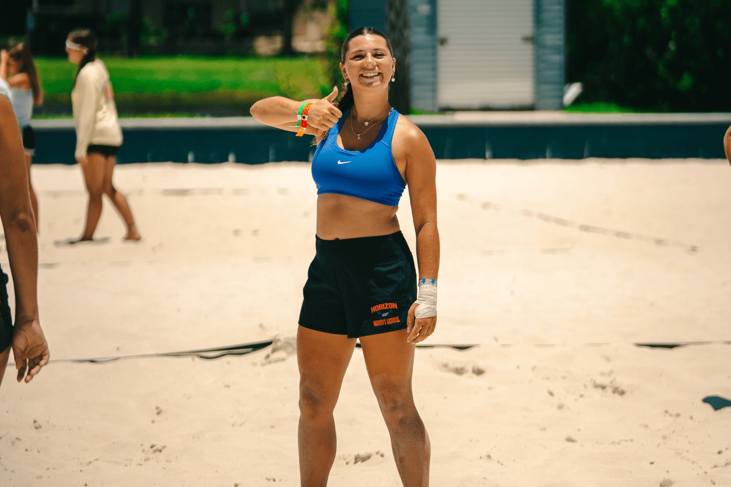 Girl playing beach volleyball gives a thumbs up at camp