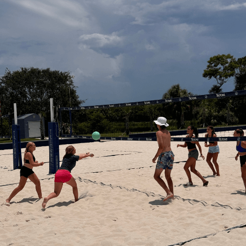 coed group playing beach volleyball at camp