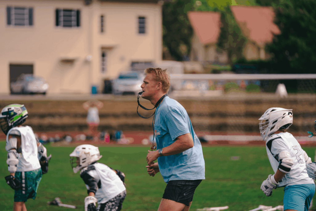 Signature Sports Camp coach in training blowing a whistle during lacrosse practice