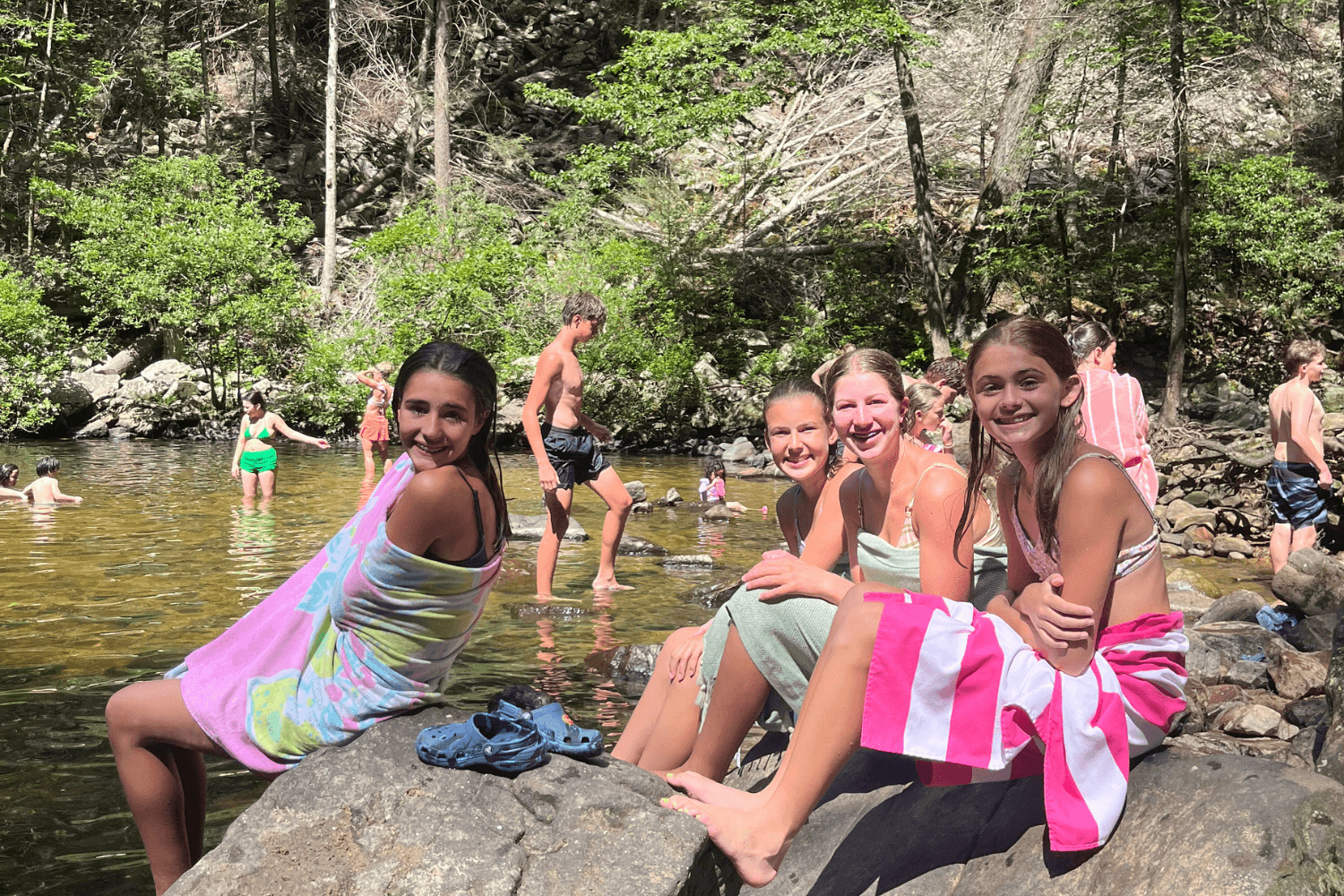 girls smile for a photo at a swimming hole during summer sports camp
