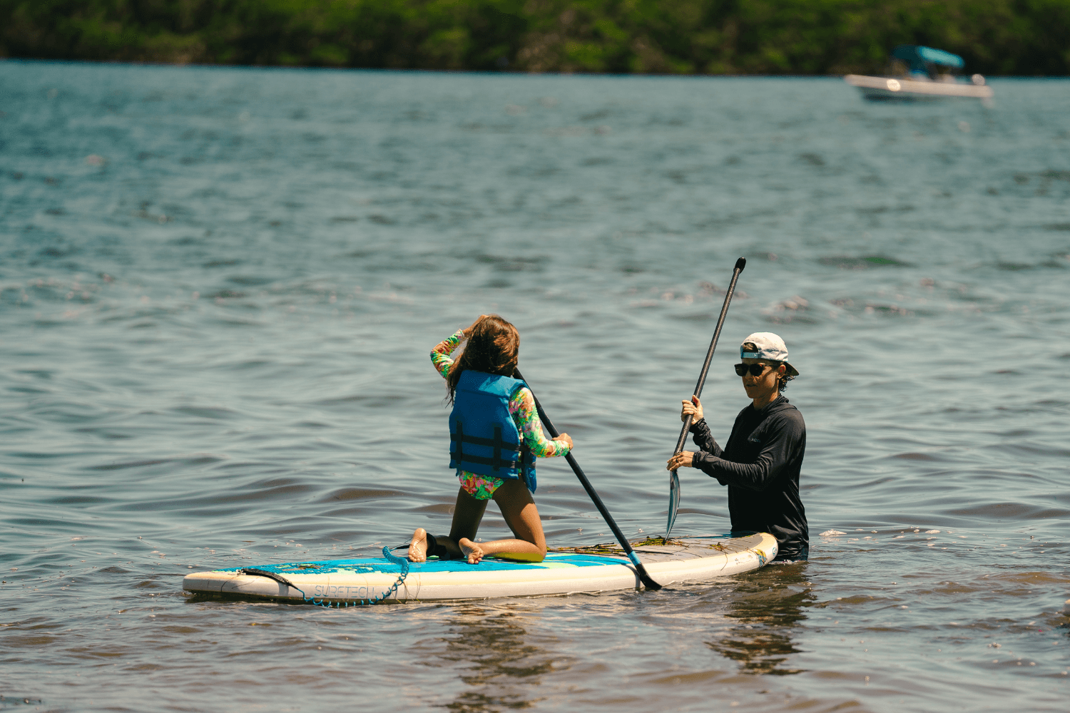 Girl is learning to paddleboard on the water at signature sports camp
