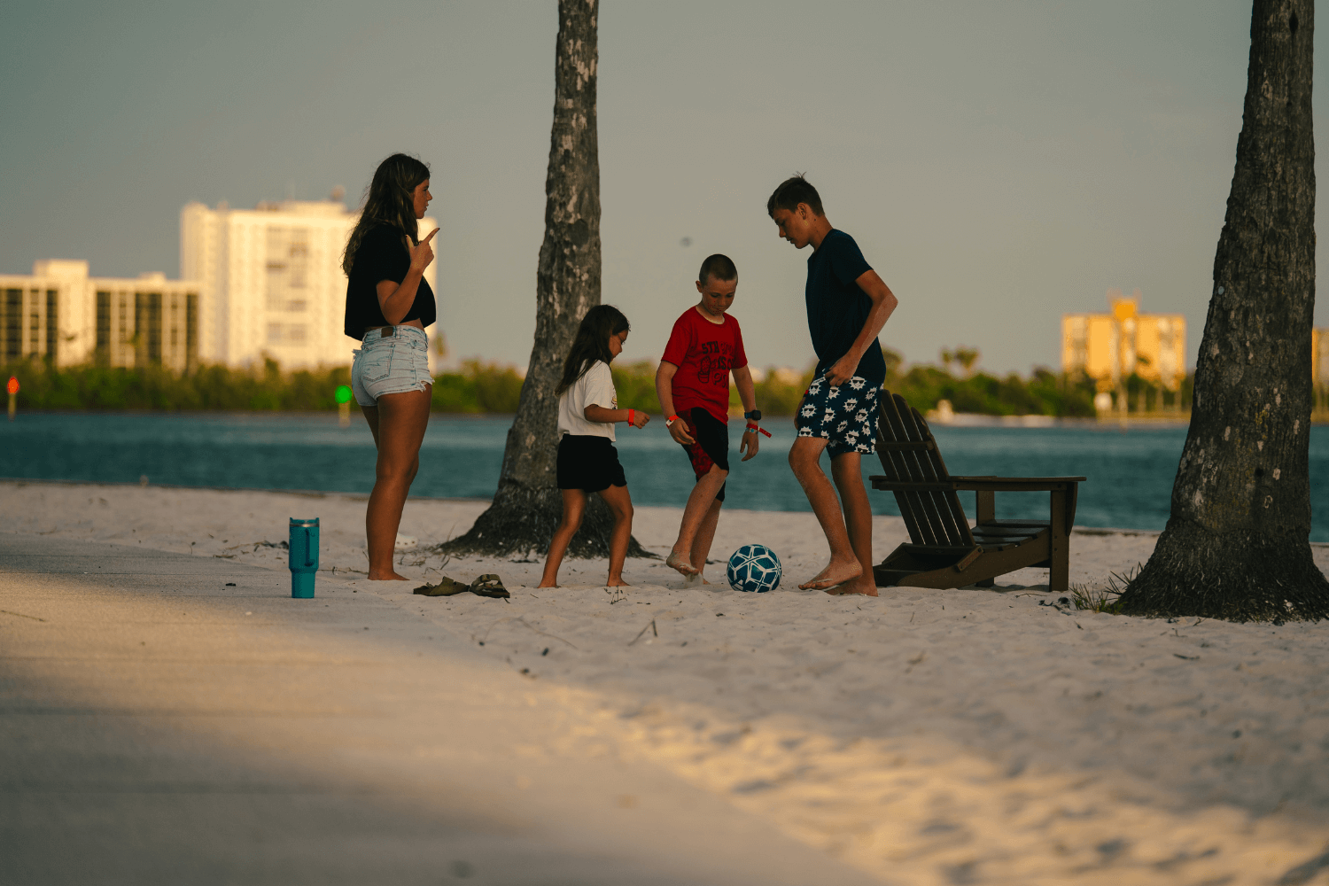 Kids at summer sports camp playing soccer on the beach