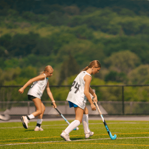 girls in a field hockey scrimmage at sports camp