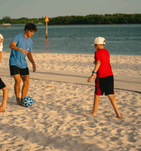 Soccer coach playing on the beach with a boy camper at Signature Sports Camps Florida.