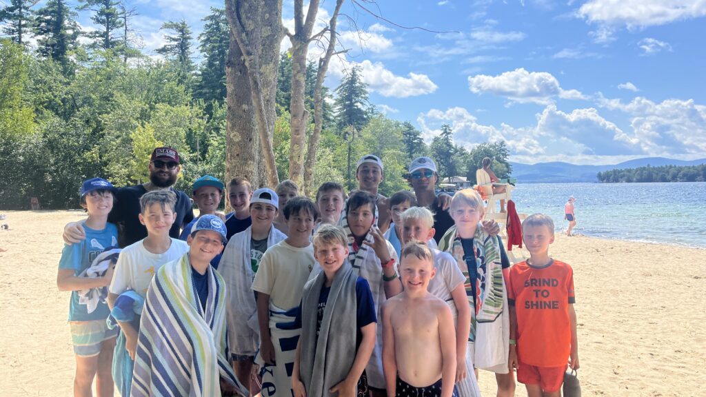 Boy campers in New England on the beach taking a group picture.