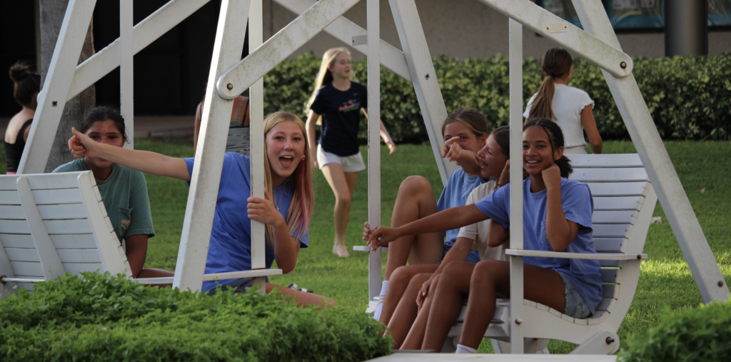Campers smiling together on a swinging bench.